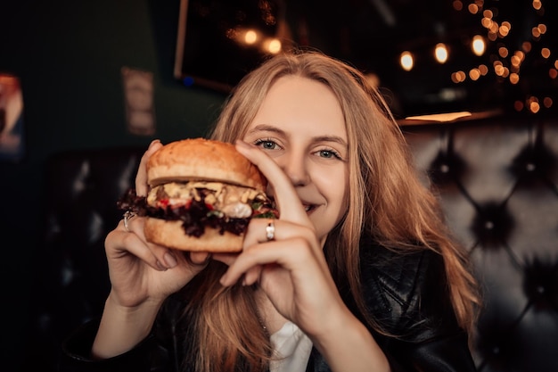 Mujer comer hamburguesa en cafe