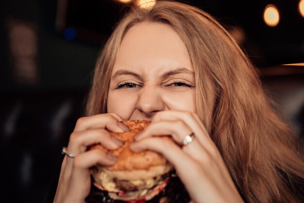 Mujer comer hamburguesa en cafe