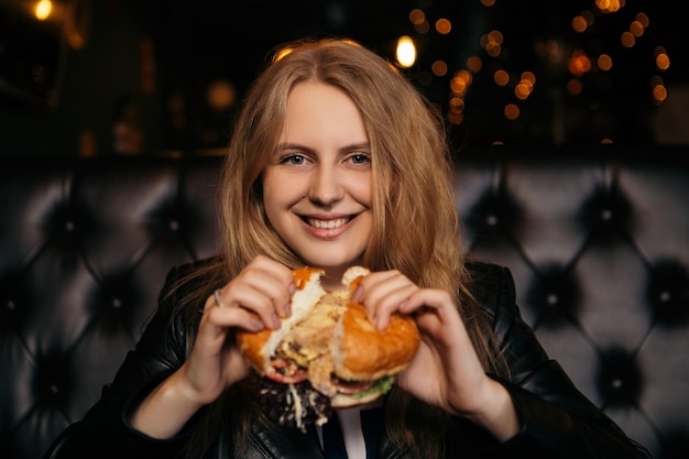 Mujer comer hamburguesa en cafe