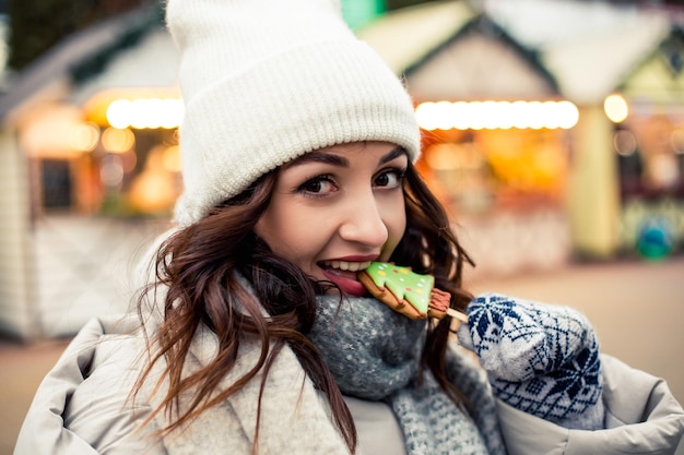 Mujer comer pan de jengibre en la feria de invierno