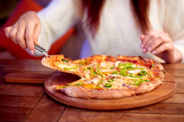 Foto mujer comer pizza en casa mujer mano toma una rebanada de pizza en rodajas con queso mozzarella tomates