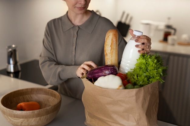 Mujer con comestibles en casa vista lateral