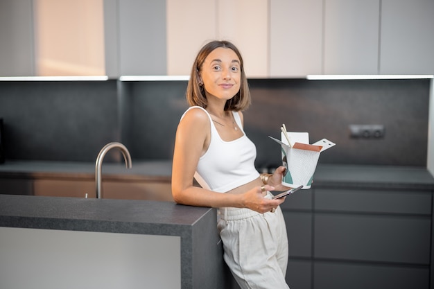 Mujer con comida para llevar y teléfono en la cocina