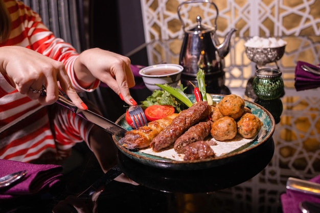 Mujer comiendo barbacoa en un café. Primer plano de manos femeninas sosteniendo un tenedor con un trozo de barbacoa.