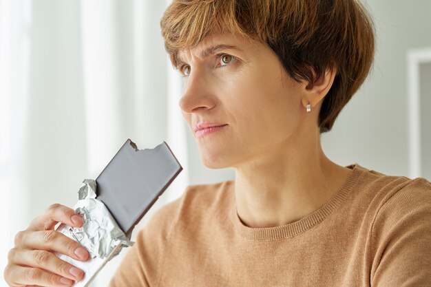 Mujer comiendo una barra de chocolate y no siente ceguera del receptor del gusto debido al coronavirus