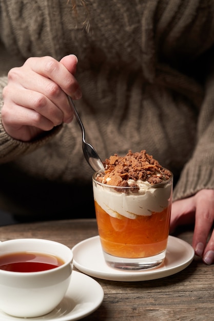 Mujer comiendo budín de caqui. Mujer desayunando con batido de caqui con crema de yogur y chocolate