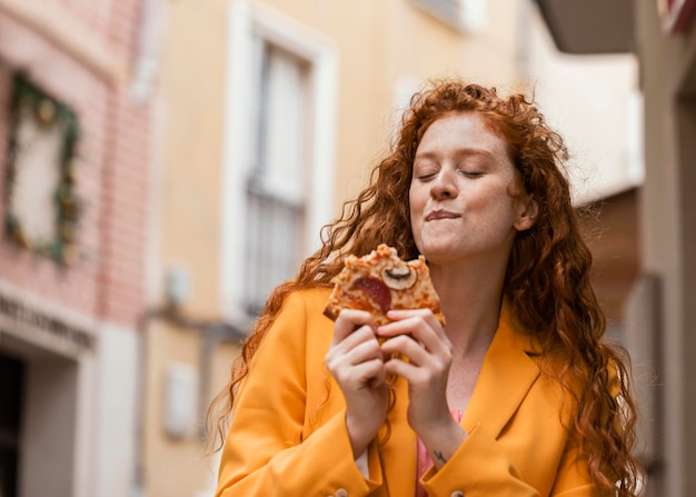 Mujer comiendo comida en la calle al aire libre