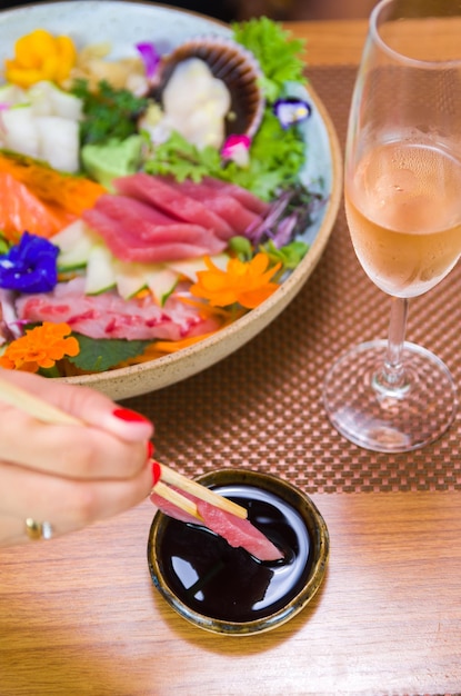 Mujer comiendo delicioso sashimi closeup en palillos