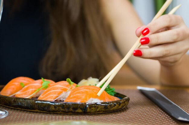 Mujer comiendo delicioso sushi closeup en palillos