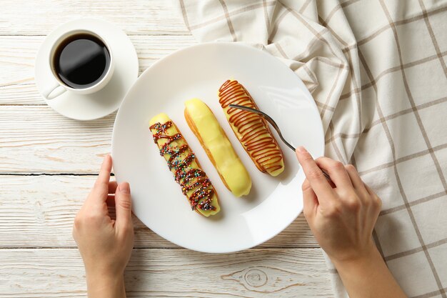 Mujer comiendo deliciosos canutillos en mesa de madera con toalla y café