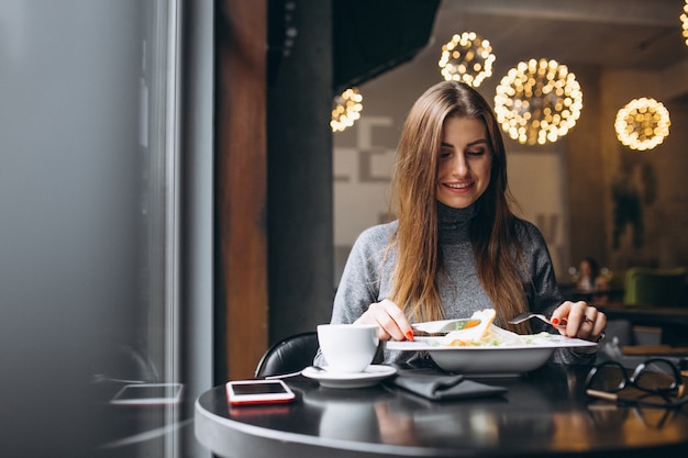 Mujer comiendo ensalada en un café