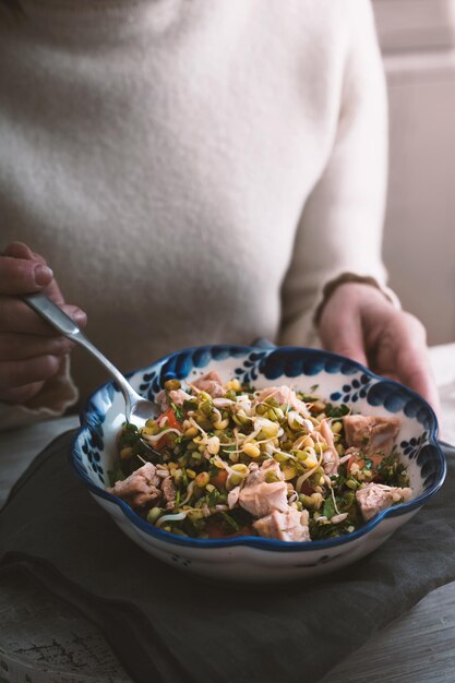 Mujer comiendo una ensalada con pollo y frijoles