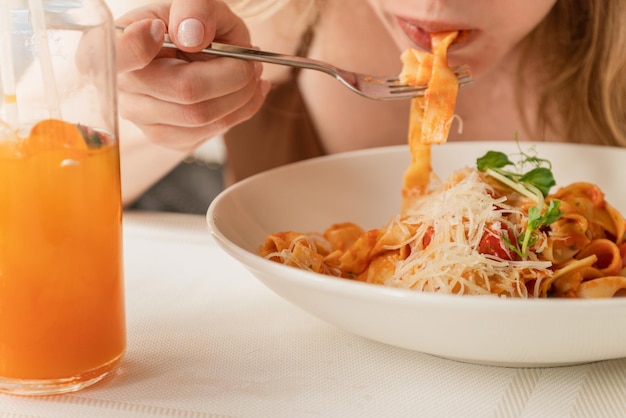 Mujer comiendo espaguetis inclinada sobre un plato de pasta