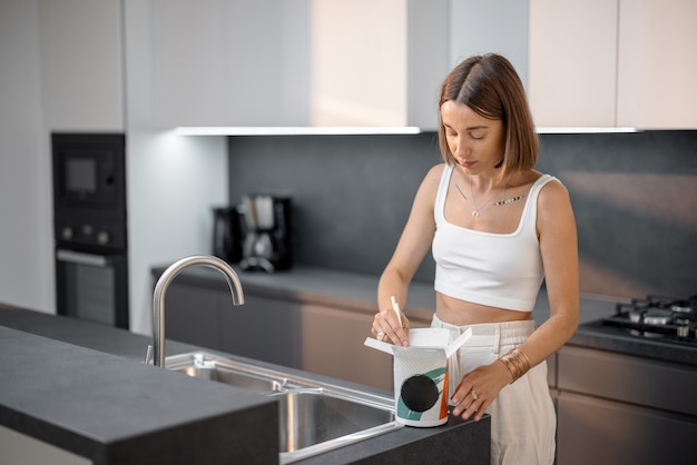 Mujer comiendo fideos de envases para llevar en casa