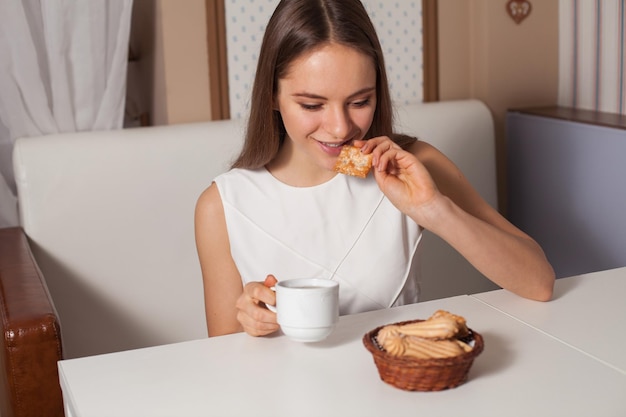 Mujer comiendo galletas y bebiendo té caliente en la cafetería