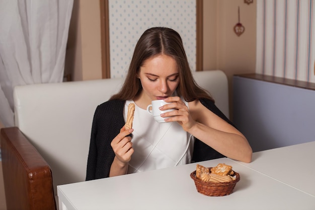 Foto mujer comiendo galletas y bebiendo té caliente en la cafetería