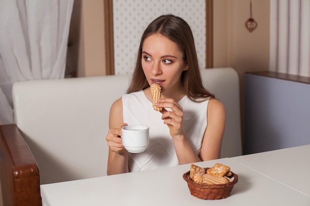 Mujer comiendo galletas y bebiendo té caliente en la cafetería