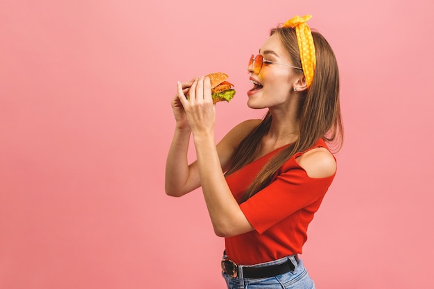 Mujer comiendo una hamburguesa en estudio