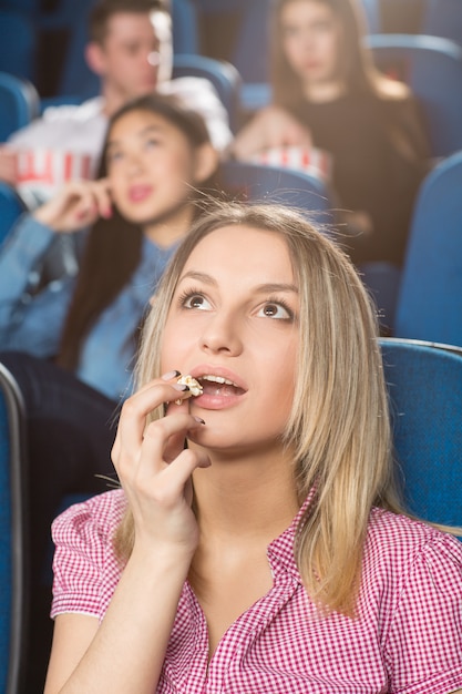 Mujer comiendo palomitas viendo una película interesante en el cine