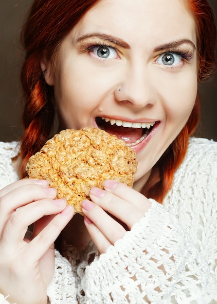 Mujer comiendo un pastel sobre un fondo blanco.