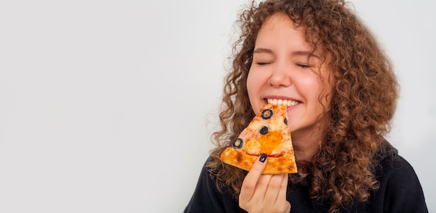 Foto mujer comiendo pizza, retrato de una mujer con una rebanada de pizza sobre un fondo blanco, con espacio de copia. el concepto de entrega de alimentos.