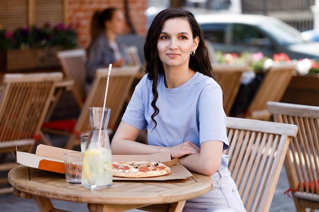 Mujer comiendo pizza sabrosa al aire libre en el café de la calle Comida rápida para llevar en un día soleado