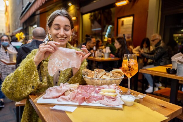 Mujer comiendo plato de carne en el bar al aire libre en Italia