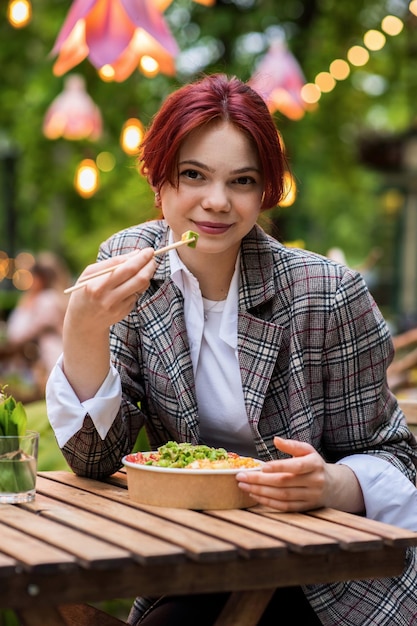 Una mujer comiendo un poke en un parque