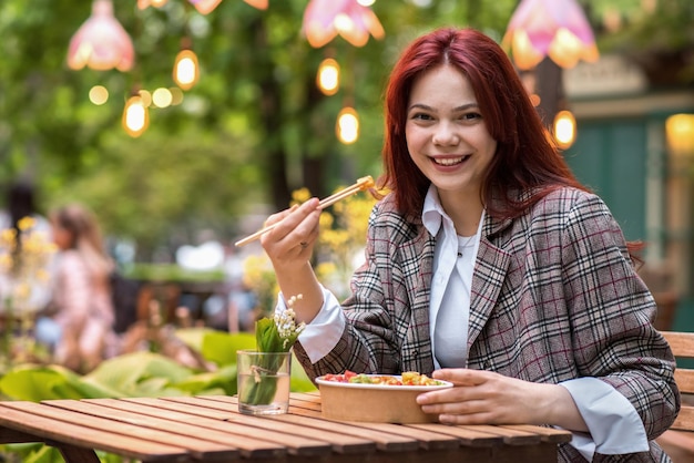 Una mujer comiendo un poke en un parque