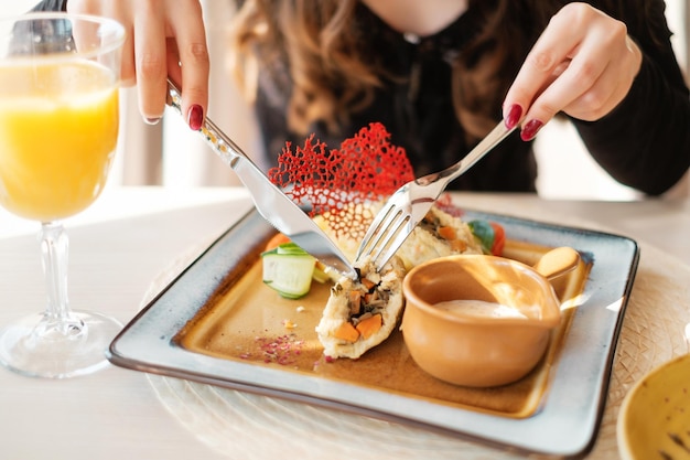 Mujer comiendo en restaurante con tenedor y cuchillo