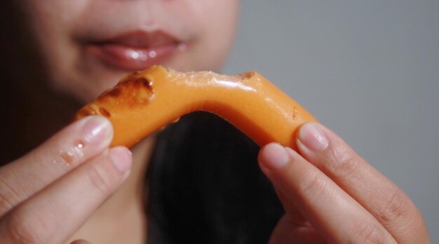 Mujer comiendo salchichas en un fondo borroso