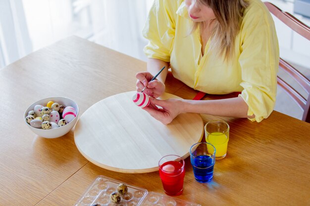 Mujer como chef pintando huevos para vacaciones de Pascua