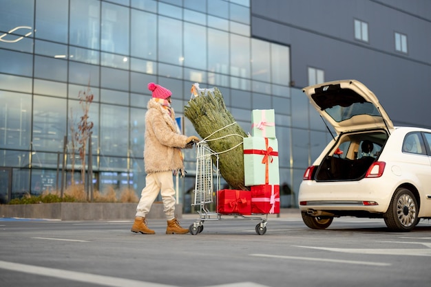 Mujer compra árbol de navidad y regalos en centro comercial