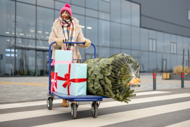 Mujer compra árbol de navidad y regalos en centro comercial