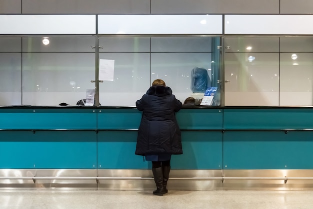 Mujer compra de pase en recepción operada. Verificación en control aduanero. cambio de moneda en el aeropuerto. comprando un boleto en un pequeño quiosco en el interior. anciana en la recepción. Ayudar.