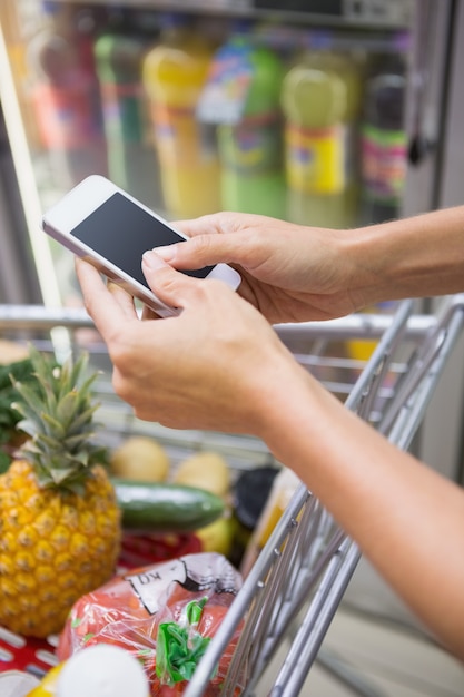 Foto mujer compra productos y usa su smartphone.