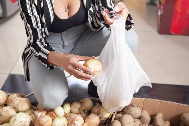 Mujer comprando cebolla en la tienda de alimentos.