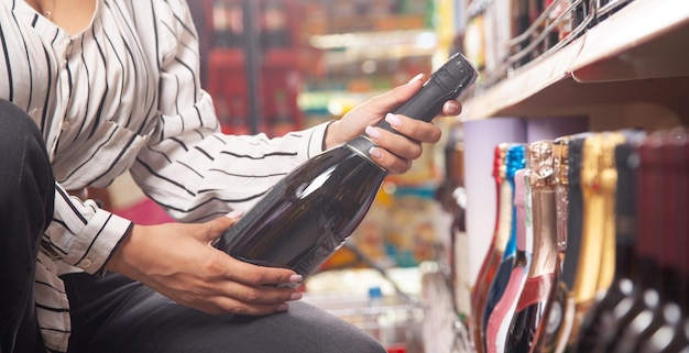 Mujer comprando champán en el supermercado