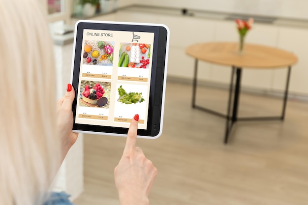 Mujer comprando comida en línea usando una tableta digital en la cocina, vista de cerca en la pantalla de una tableta. Concepto de comprar en línea usando dispositivos móviles.