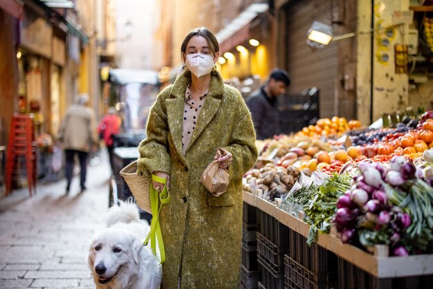 Mujer comprando comida en el mercado callejero con un perro durante la pandemia