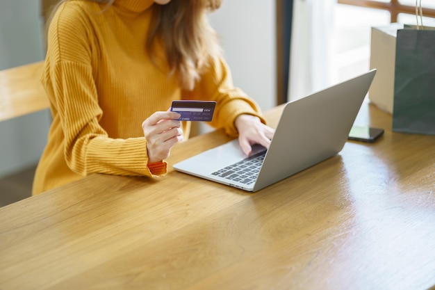 Mujer comprando en una computadora portátil con tarjeta de crédito para compras de comercio electrónico en línea de Internet gastando dinero Compras en línea Concepto de tecnología de computadora portátil de teléfono móvil