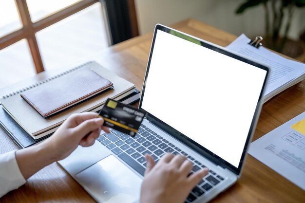 Mujer comprando en una computadora portátil con tarjeta de crédito para compras de comercio electrónico en línea de Internet gastando dinero Compras en línea Concepto de tecnología de computadora portátil de teléfono móvil