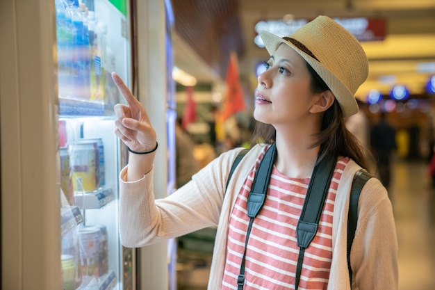 mujer comprando cosas de la máquina expendedora. no estoy seguro de qué beber. luciendo incierto pero relajante.