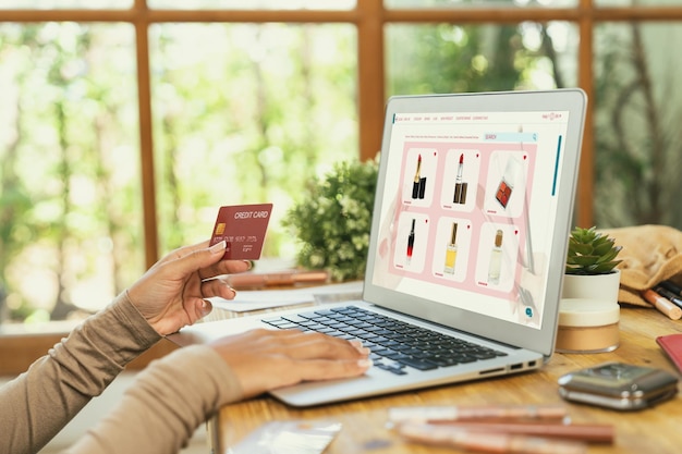 Foto mujer comprando en línea en el mercado de internet buscando artículos en venta para un estilo de vida moderno y usando tarjeta de crédito para pagos en línea desde una billetera protegida por un software crucial de seguridad cibernética