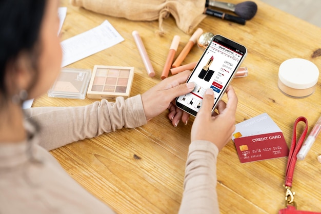 Mujer comprando en línea en el mercado de Internet buscando artículos en venta para un estilo de vida moderno y usando tarjeta de crédito para pagos en línea desde una billetera protegida por un software crucial de seguridad cibernética