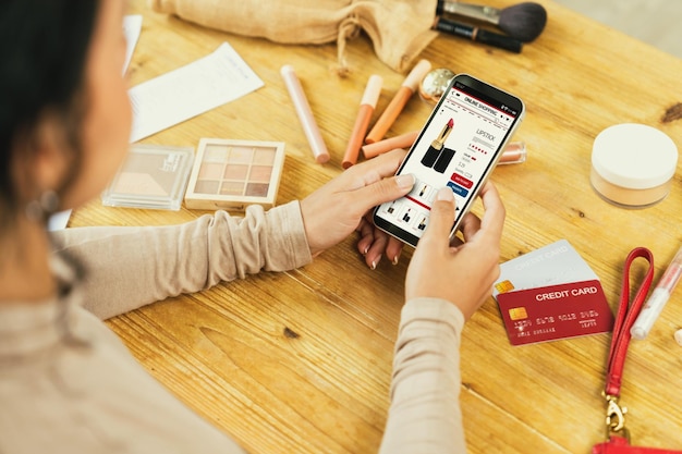 Mujer comprando en línea en el mercado de Internet buscando artículos en venta para un estilo de vida moderno y usando tarjeta de crédito para pagos en línea desde una billetera protegida por un software crucial de seguridad cibernética