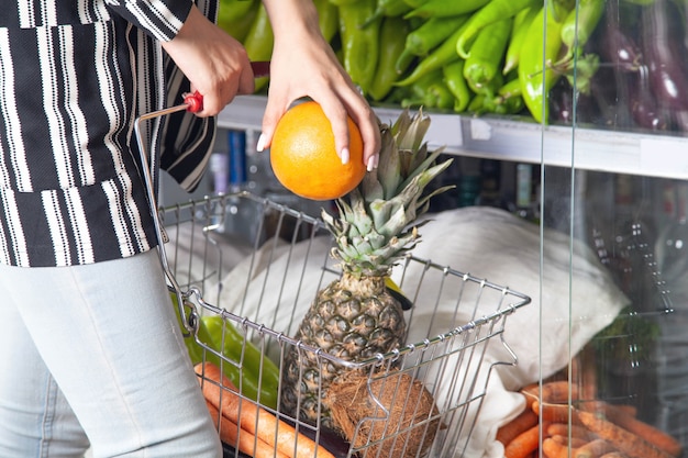 Mujer comprando naranja en la tienda de alimentos.