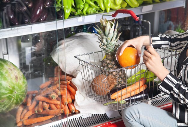 Mujer comprando naranja en la tienda de alimentos.