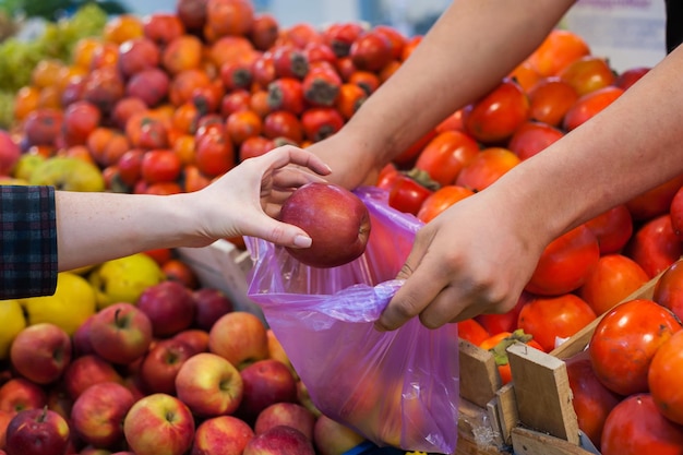 Mujer comprando verduras frescas en el mercado callejero