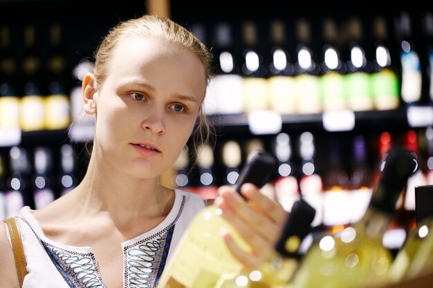 Mujer de compras de alcohol en una tienda de botella